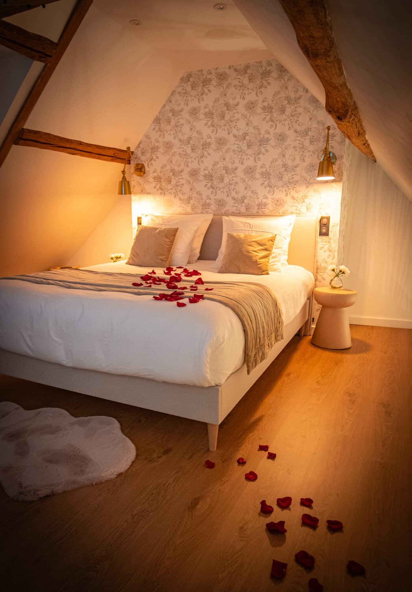 Lit queen size décoré de pétales de roses dans la suite La Douce en Normandie par La Parenthèse