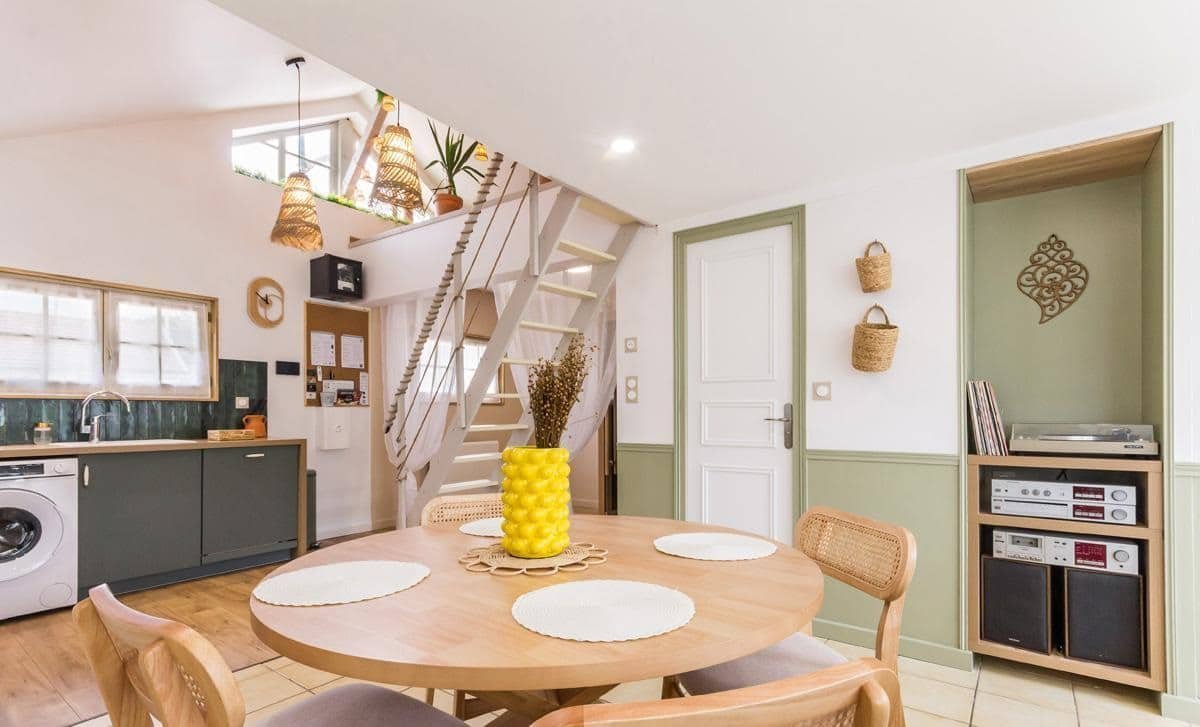 Pièce de vie ouverte avec coin repas et escalier dans l’appartement La Parenthèse en Normandie